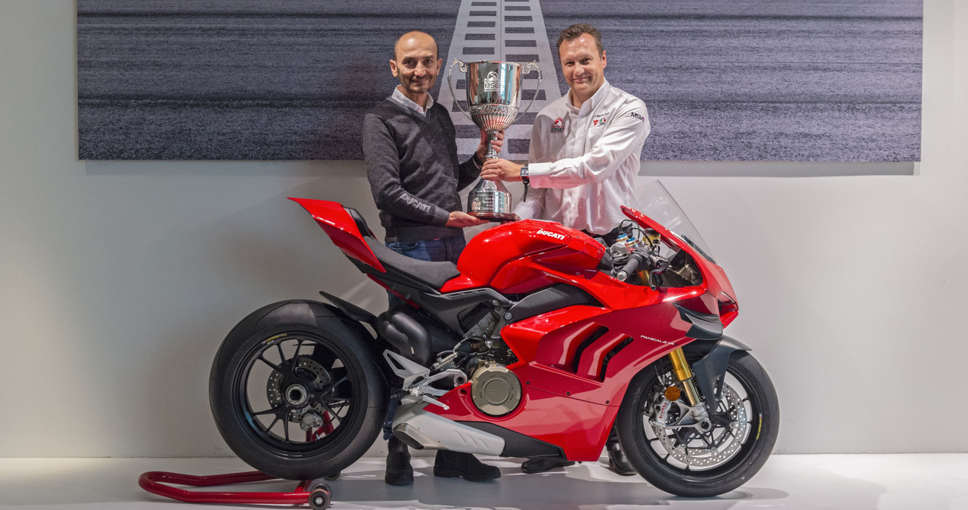 Ducati CEO Claudio Domenicali (left) accepting the British Superbike (BSB) Manufacturer Championship trophy from BSB Series Director Stuart Higgs (right) at Ducati’s headquarters in Bologna, Italy. Photo courtesy of Ducati.