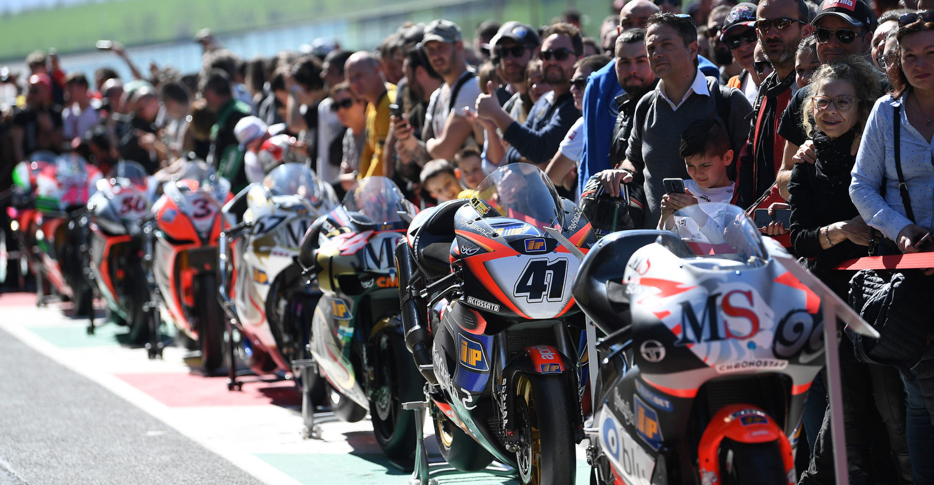 Fans and retired Aprilia racebikes lined up at Aprilia All Stars in 2019. Photo courtesy of Aprilia.