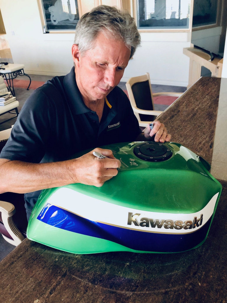 Four-time 500cc Grand Prix World Champion Eddie Lawson autographing the fuel tank of the 1999 Kawasaki ZRX1100 tribute bike being raffled by AHRMA. Photo courtesy AHRMA.