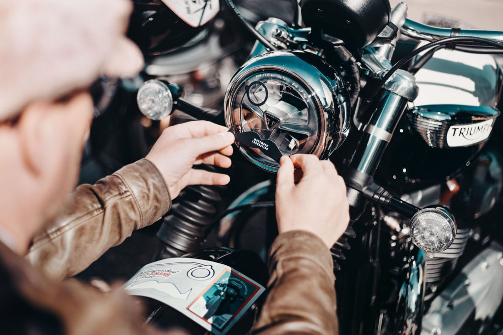 A participant putting a DGR decal on the headlight of his motorcycle. Photo courtesy Triumph.