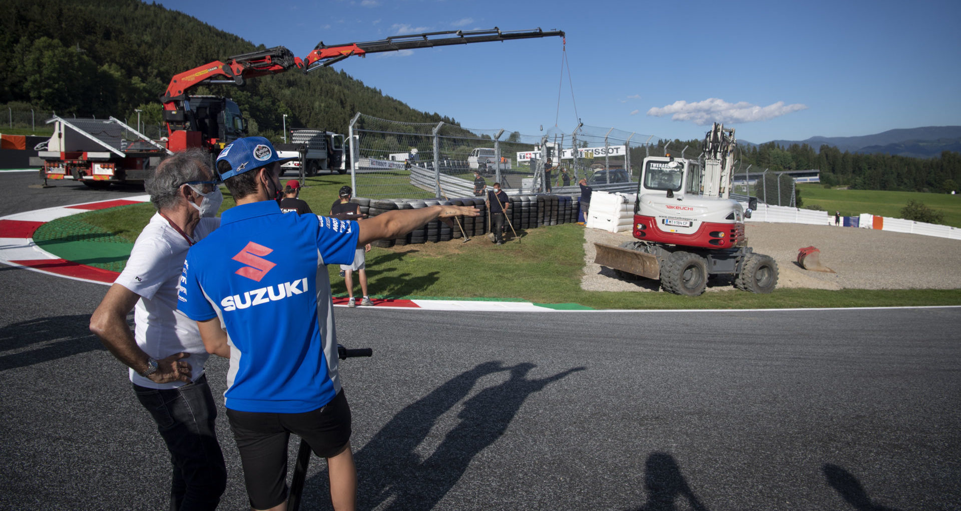 Alex Rins (right) talks to FIM Grand Prix Safety Officer Franco Uncini (left) as work is undertaken to erect new safety barriers in Turn Three at Red Bull Ring. Photo courtesy Dorna.