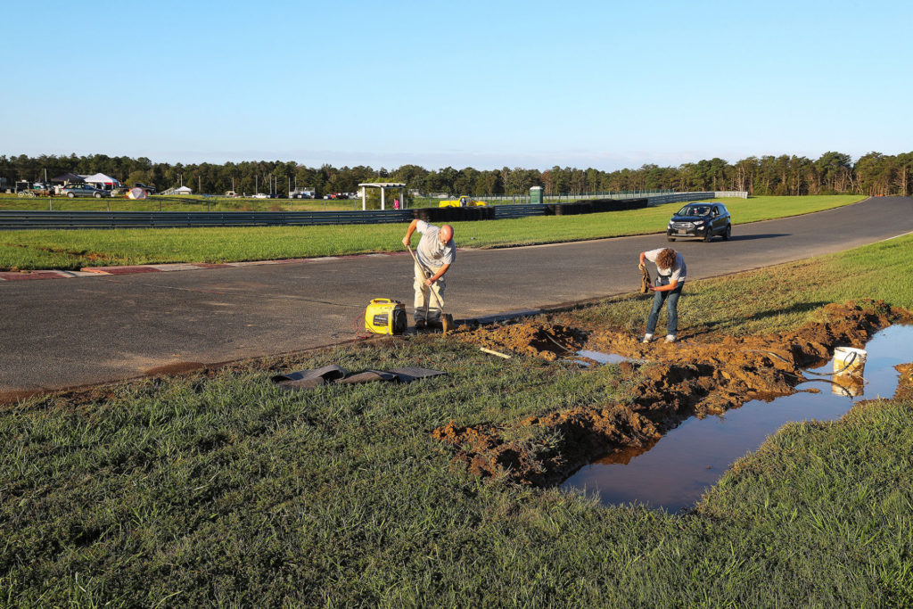 Heavy rains Thursday night caused drainage problems on Friday, with rivers running across the pavement and puddles forming on the pavement. On Friday evening track employees and volunteers worked to direct the water away from the track, by digging drainage ditches. Photo by Brian J. Nelson.