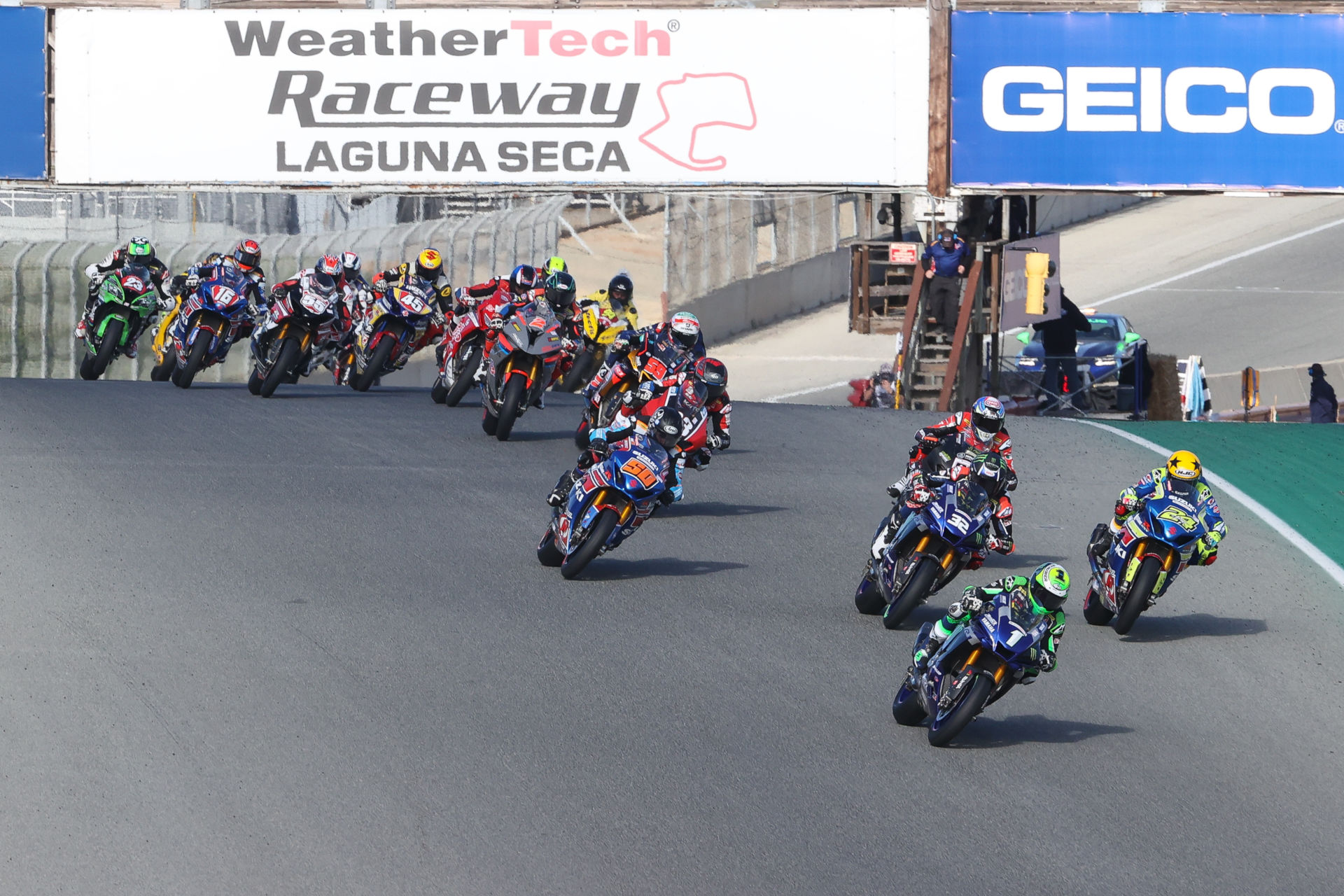 Cameron Beaubier (1) leads Toni Elias (24), Jake Gage (32), Lorenzo Zanetti (behind Gagne), Bobby Fong (50), Kyle Wyman (behind Fong), Niccolo Canepa (behind Wyman), Josh Herrin (2), and the rest of the HONOS Superbike field during a race start Sunday at Laguna Seca. Photo by Brian J. Nelson, courtesy MotoAmerica.