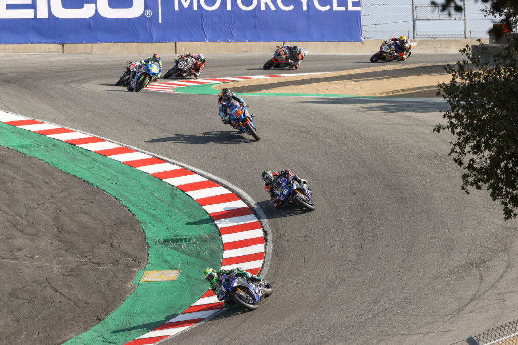 Cameron Beaubier (1) leads Jake Gagne (32), Bobby Fong (50), Toni Elias (24), Kyle Wyman (behind Elias), Lorenzo Zanetti (87), Josh Herrin (2), and Cameron Petersen (45) down the Corkscrew at the start of HONOS Superbike Race One. Photo by Brian J. Nelson, courtesy MotoAmerica.