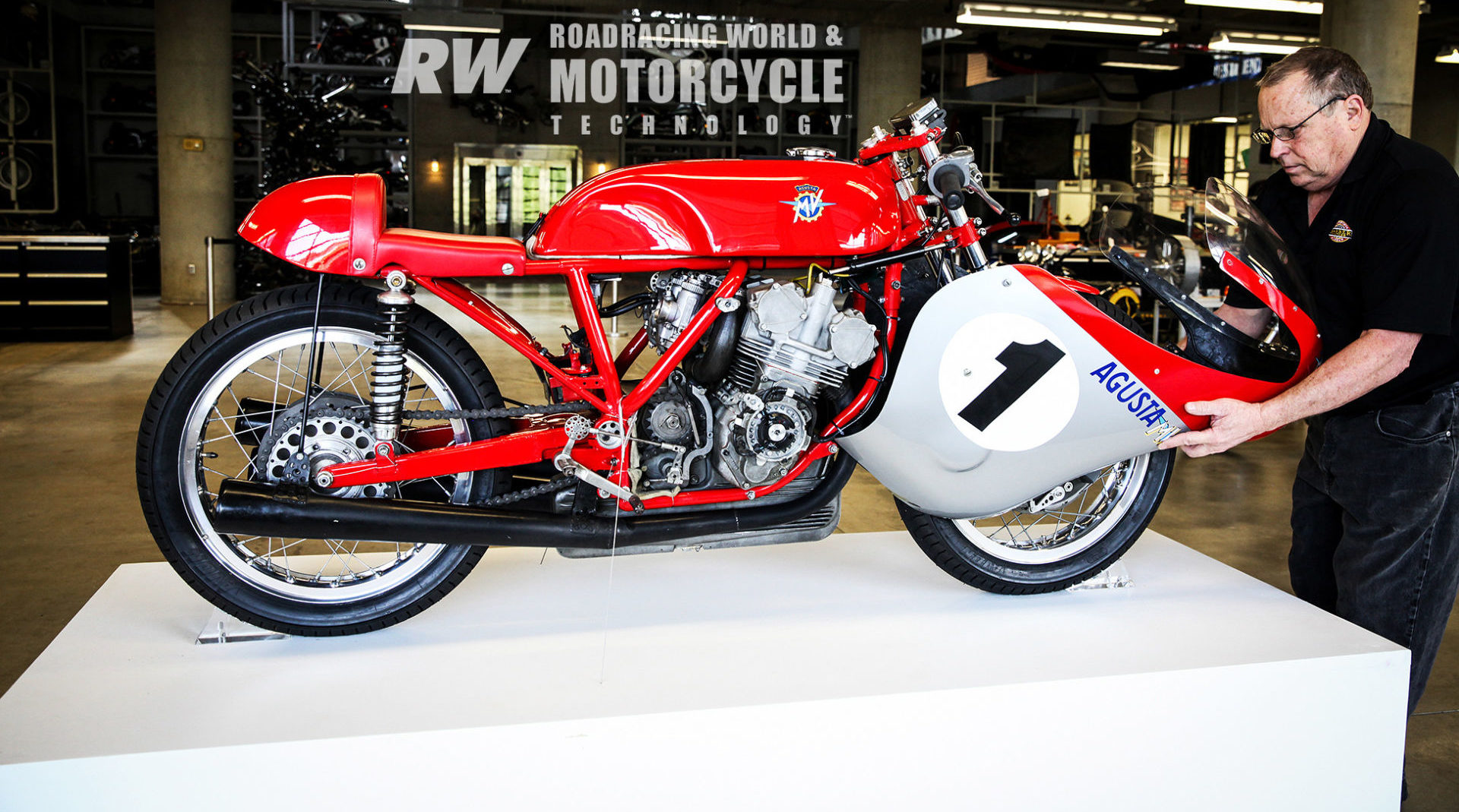 Chuck Huneycutt removes the 1967 MV Agusta 500 Triple's fairing in preparation for a photo shoot. The bike is held in place on a portable display pedestal by two clear plastic wheel chocks and guy wires on each side. Photo by Brian Case/Barber Museum.