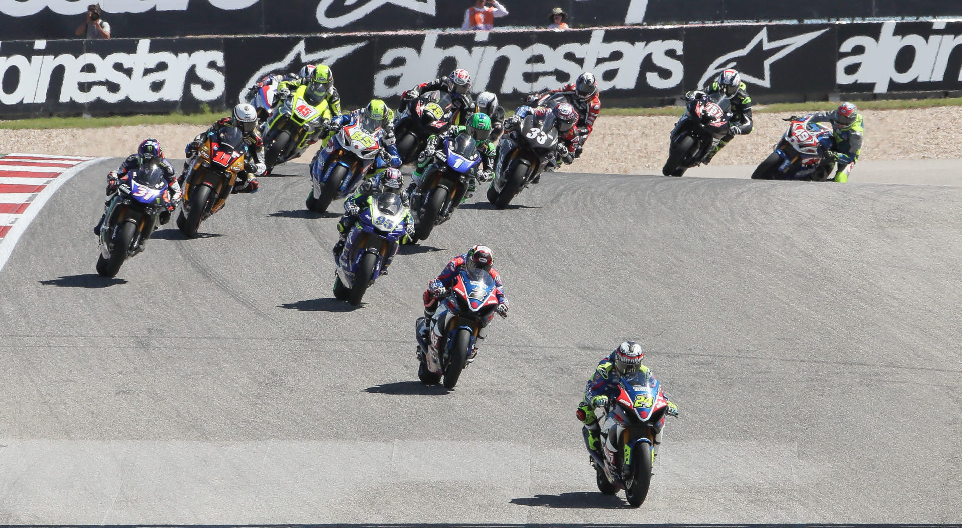 The start of a MotoAmerica Superbike race at COTA in 2019 with Toni Elias (24) leading Josh Herrin (2), JD Beach (95), Garrett Gerloff (31), Mathew Scholtz (11), Cameron Petersen (45), Jake Lewis (85), Cameron Beaubier (1), David Anthony (25), Kyle Wyman (33) and the rest of the field out of Turn One. Photo by Brian J. Nelson.