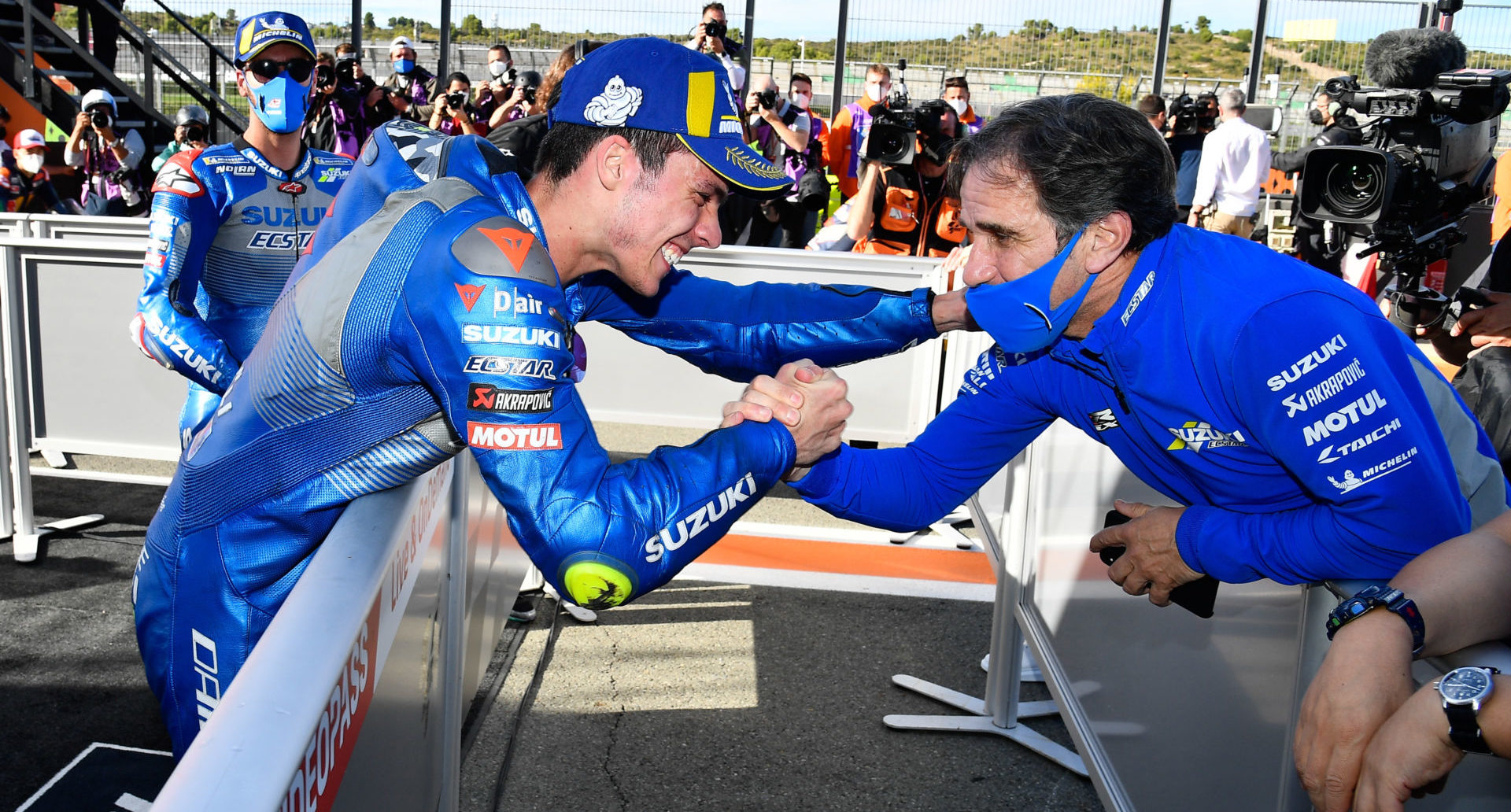 Davide Brivio (right) shakes hands with 2020 MotoGP World Champion Joan Mir (left). Mir's teammate Alex Rins looks on in the background. Photo courtesy Team Suzuki Press Office.