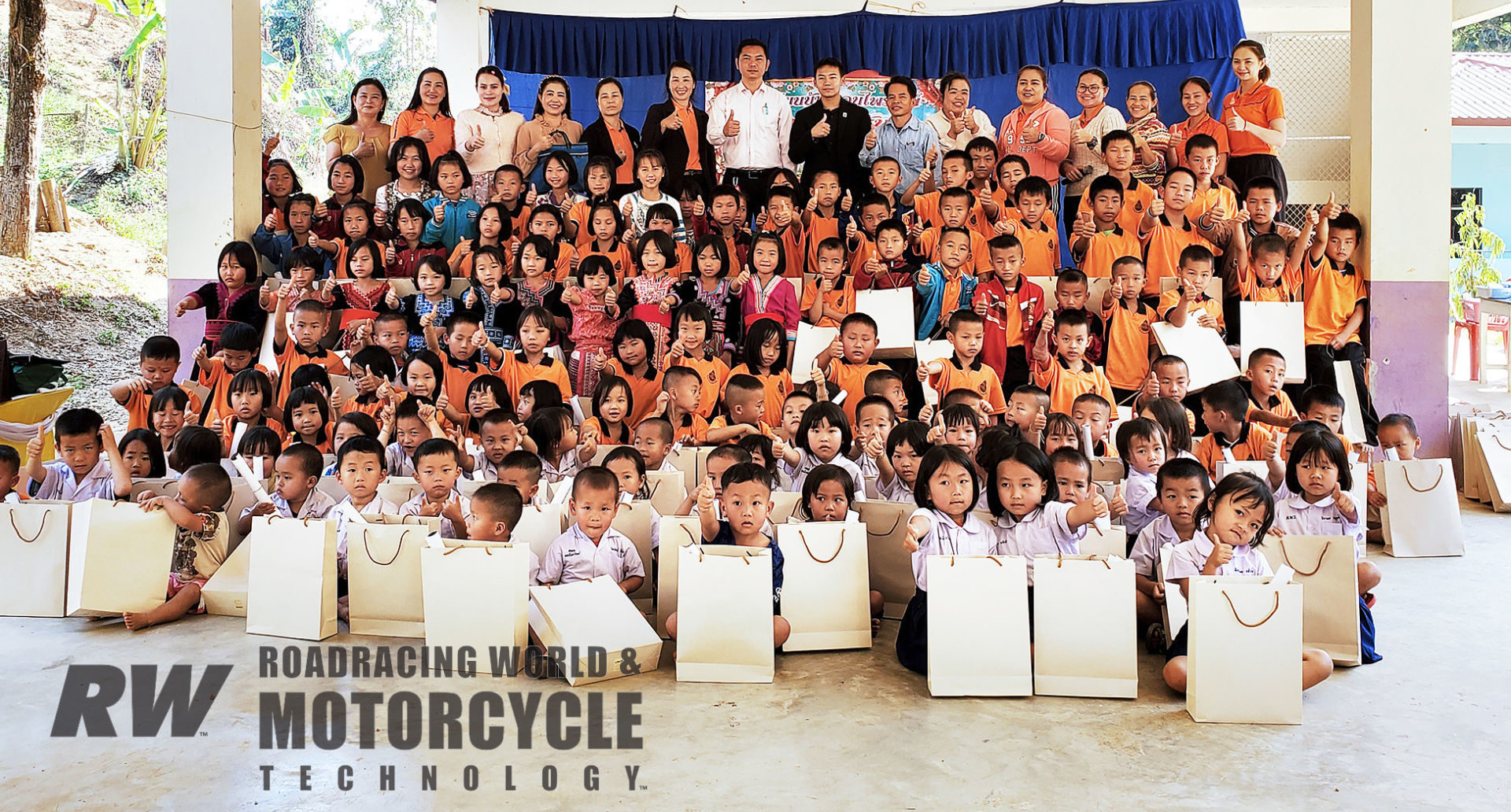 Aden Thao (seen in a black shirt in the back row center) poses with students, teachers, and administrators after delivering school supplies and money for a new cafeteria to Ban Don Phraiwan School in Mae Sanan, Thailand.