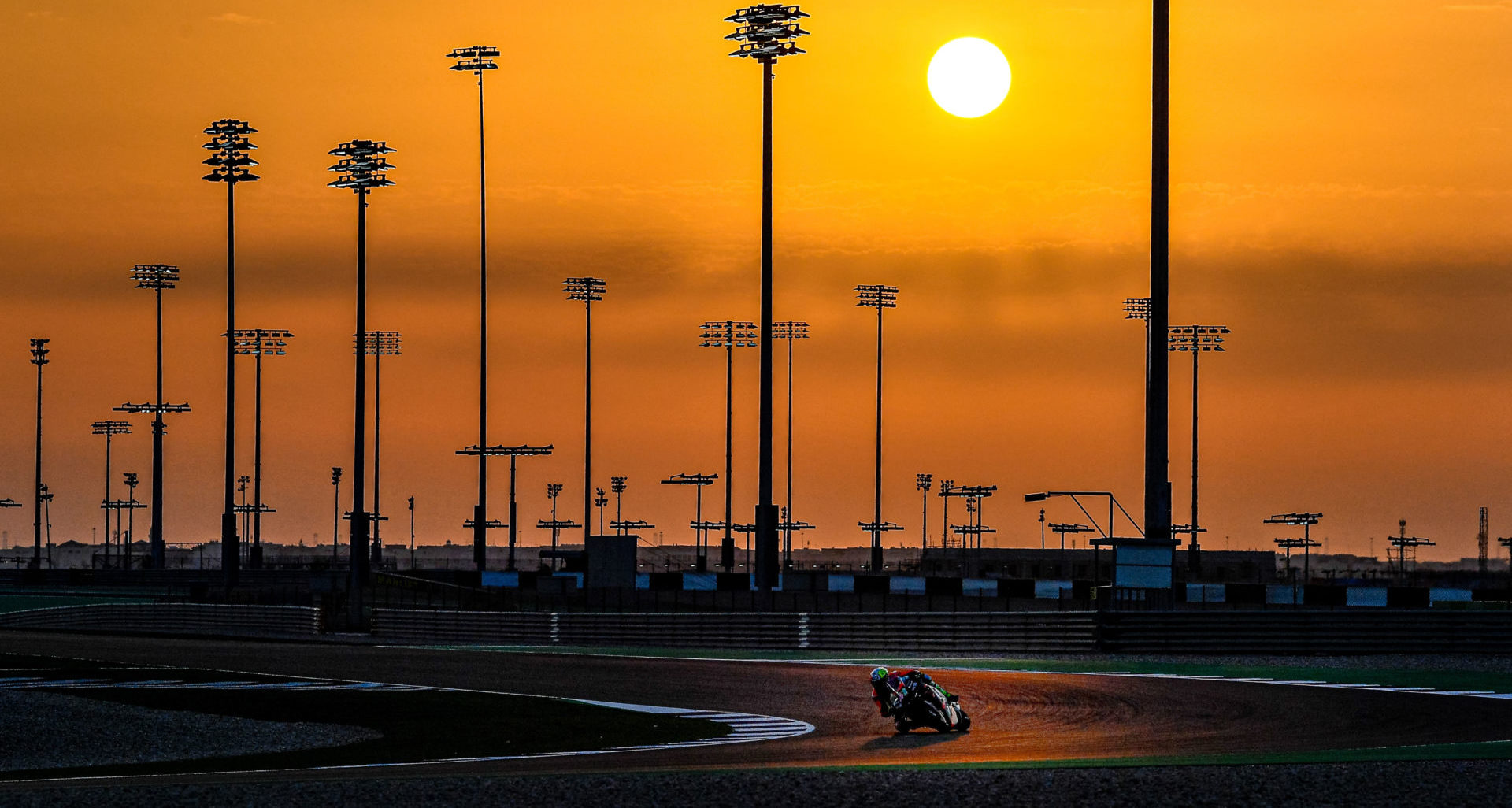 Aleix Espargaro rides through the twilight at Losail International Circuit, in Qatar. Photo courtesy Dorna.