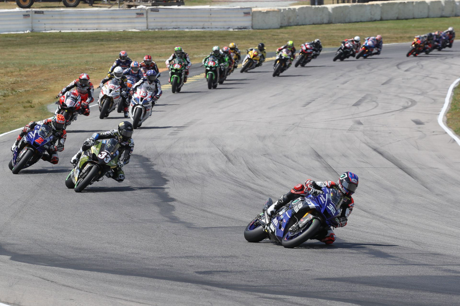 Jake Gagne (32) leads Kyle Wyman (33), Josh Herrin (2), Loris Baz (76), Travis Wyman (10), Hector Barbera (80), Bobby Fong (50) and the rest of the field at the start of Superbike Race Two. Photo by Brian J. Nelson, courtesy Yamaha.