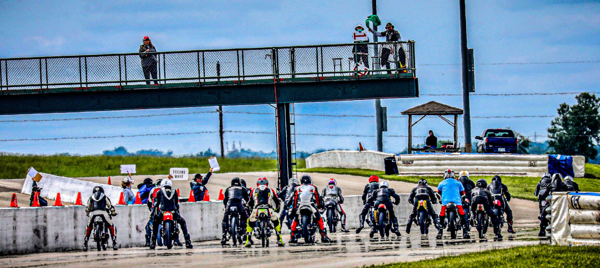 Starter Ed Bargy waves the green flag to start a combined Classic Sixties, Classic Sixties 650, Sportsman 500, Formula 250, and 250 Grand Prix race during the AHRMA Classic MotoFest in the Heartland at Heartland Motorsports Park, in Topeka, Kansas. Photo by Chuck Hanna, courtesy AHRMA.