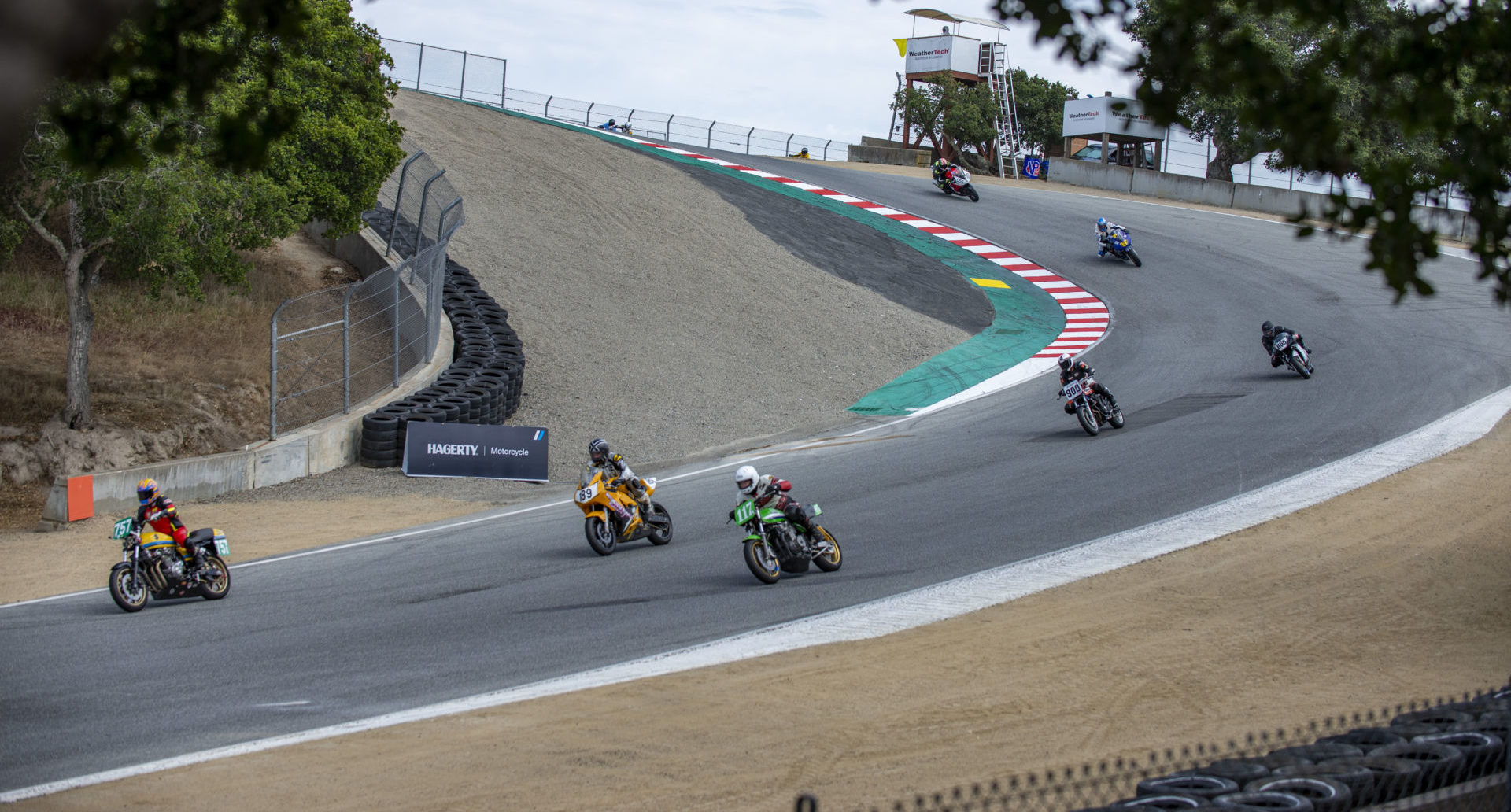 AHRMA racers Michael Butler (757), John Deuser (189), Dave Crussell (119), Mathew Morse (055), Mike Root (R66), Alex Spanos (L29), and Kevin McKee (900) in action at Laguna Seca. Photo by Kevin McIntosh, courtesy AHRMA.