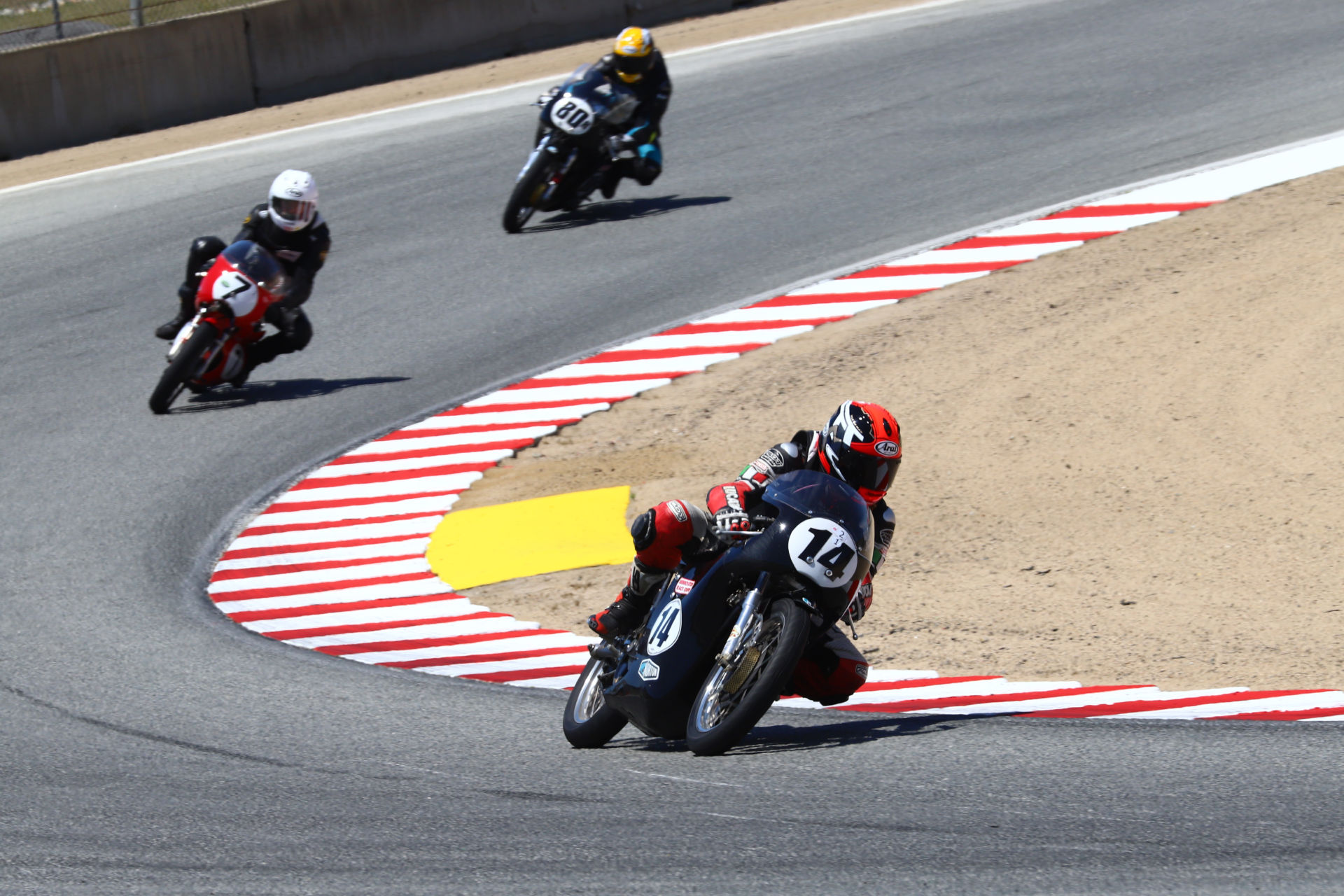 Brian Larrabure (14) leads David Roper (7) and Helmi Niederer (80) during an AHRMA Vintage Cup race at Laguna Seca. Photo by etechphoto.com, courtesy AHRMA.