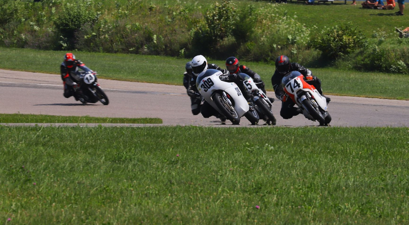 Tim Joyce (309), Wes Orloff (74), Andrew Mauk (X95, behind Joyce), and Brian Larrabure (14) at the start of an AHRMA Vintage Cup race at Gingerman Raceway. Photo by etechphoto.com, courtesy AHRMA.