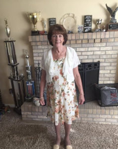 Linda Hopkins posing in front of a few of son John's trophies from early in his career, in her living room, 2019. Photo courtesy Hopkins Family.