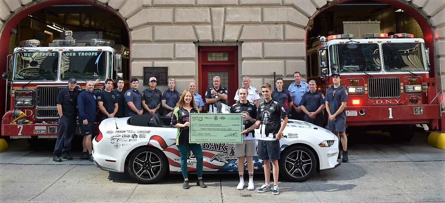 BARTCON Racing riders Dominic Doyle (front right), Anthony Mazziotto (second from right), and Tosha Lackey (front left) hold a $2,000 ceremonial check representing a donation to the Answer The Call foundation. BARTCON Racing owner Colin Barton is standing in the doorway directly behind the check. Photo by Robert Lackey, courtesy BARTCON Racing.