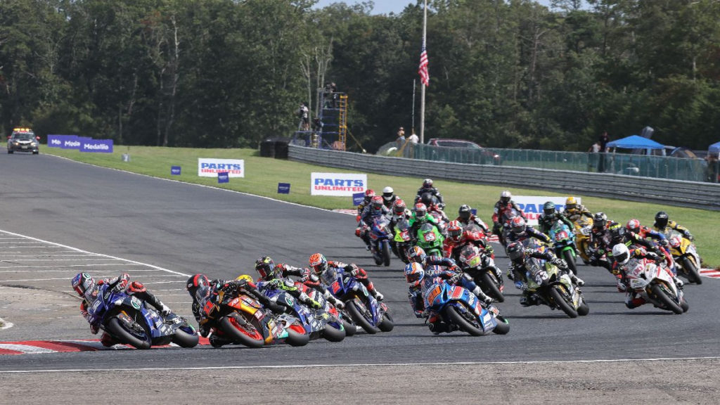 Jake Gagne (32) leads Mathew Scholtz (11), Toni Elias (behind Scholtz), Loris Baz (behind Elias), Josh Herrin (2), Bobby Fong (50), Cameron Petersen (behind Fong), Kyle Wyman (33), Hector Barbera (80) and the rest of the field at the start of Race One. Photo by Brian J. Nelson, courtesy MotoAmerica.