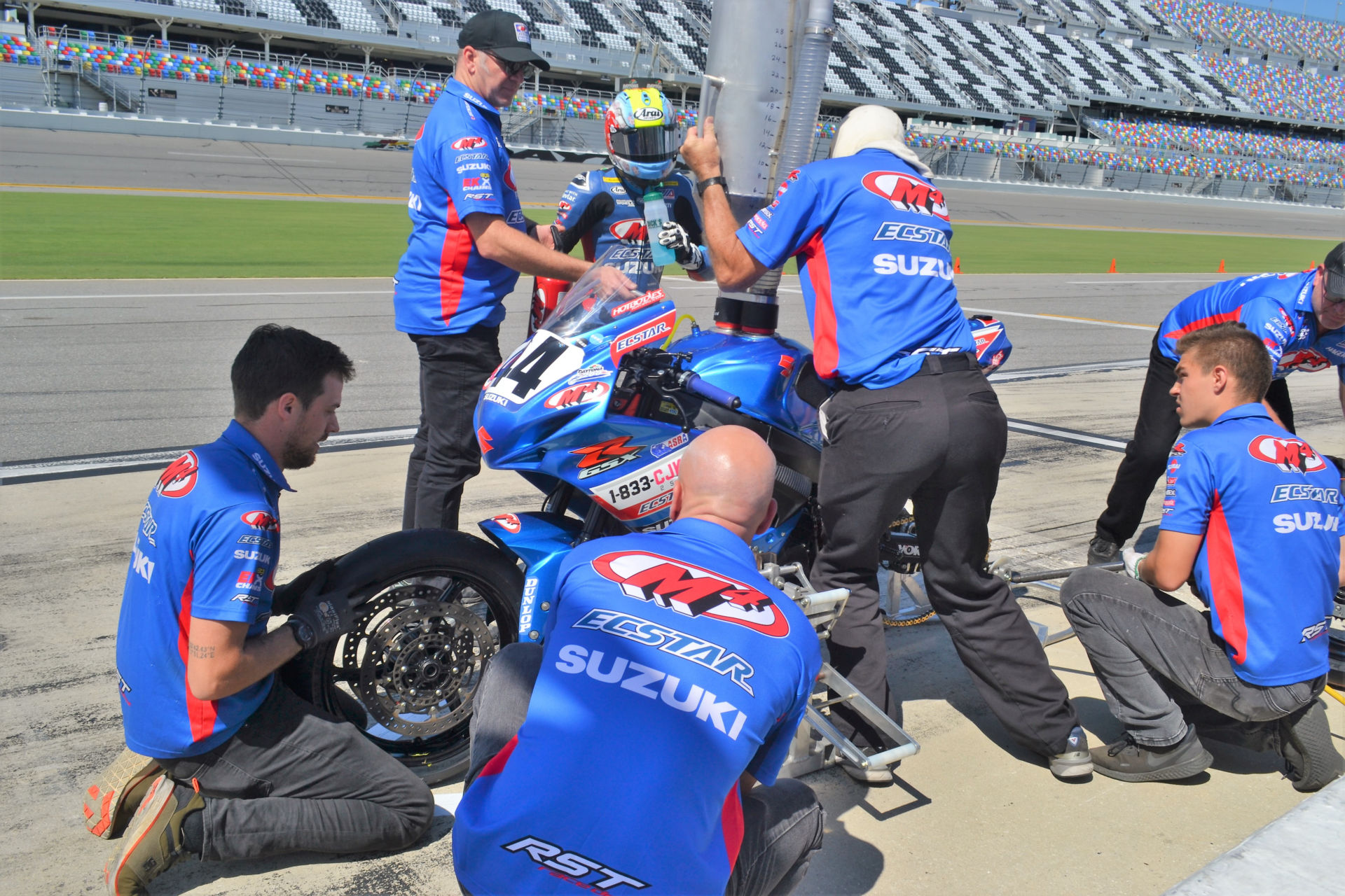 Sam Lochoff takes a quick drink while his M4 ECSTAR Suzuki crew refuels and installs new Dunlop tires on his GSX-R600 during his only pit stop. Photo by David Swarts.