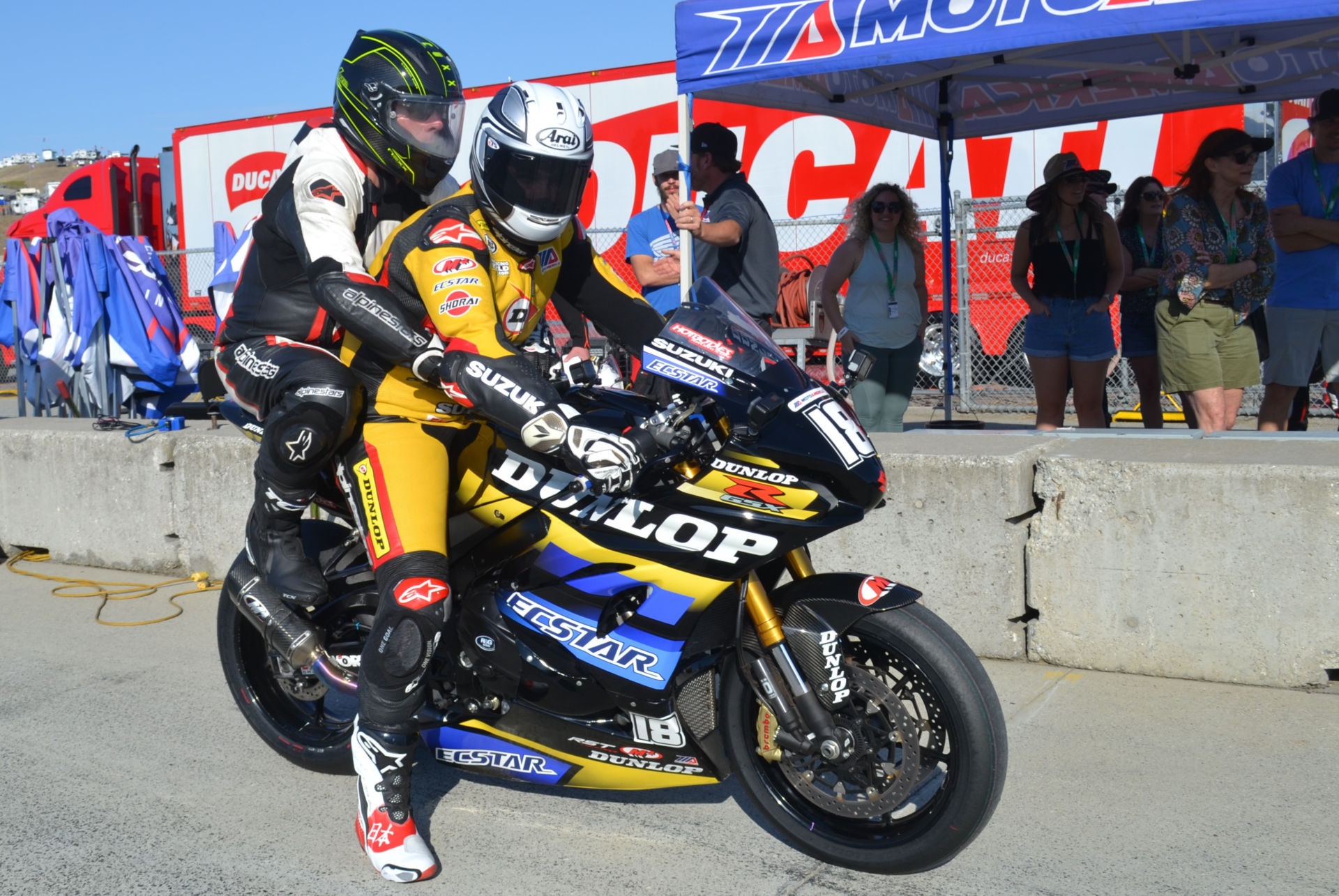 Medallia President and CEO Leslie Stretch about to go for a ride with former Pro Superbike racer Chris Ulrich on the Dunlop ECSTAR Suzuki two-seat Superbike at WeatherTech Raceway Laguna Seca in 2021. Photo by David Swarts.