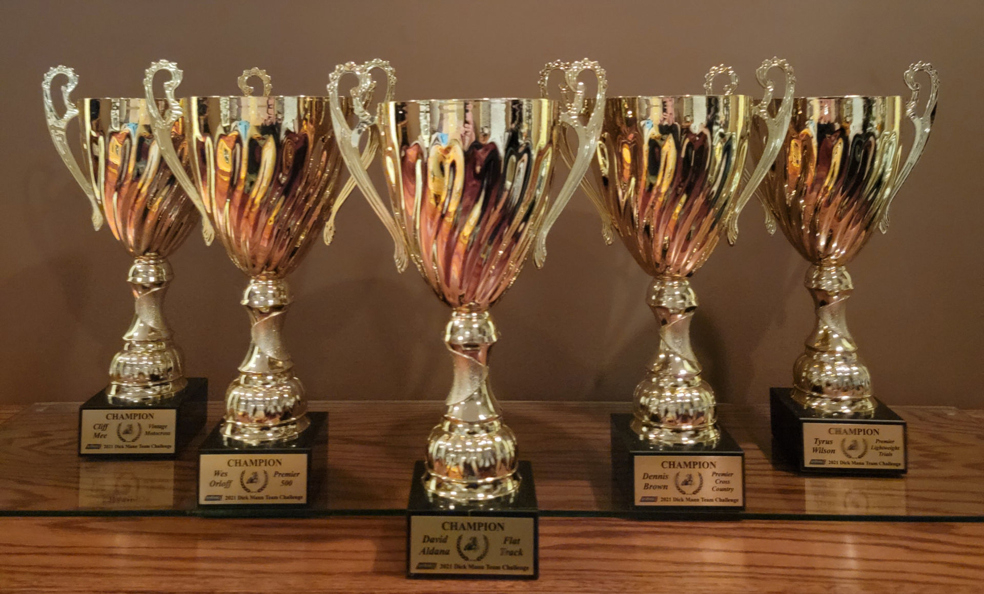 The 2021 Inaugural Dick Mann Team Challenge trophies. Team winners include (from left to right) Cliff Mee (Vintage MX), Wes Orloff (Road Racing - Premier 500), David Aldana (Flat Track), Dennis Brown (Premier Cross Country), and Tyrus Wilson (Premier Lightweight Trials). Photo by Tim Terrell.