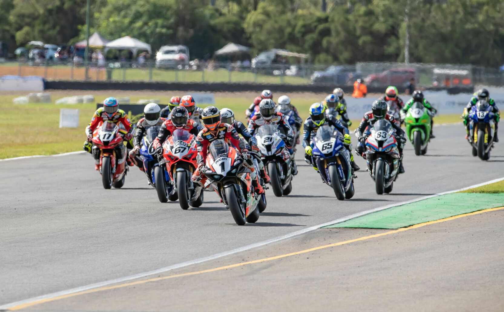 Wayne Maxwell (1) leads Mike Jones (behind Maxwell) and the rest of the field at the start of Australian Superbike Race 2 at Queensland Raceway. Photo by Karl Phillipson/@optikalphoto, courtesy ASBK.