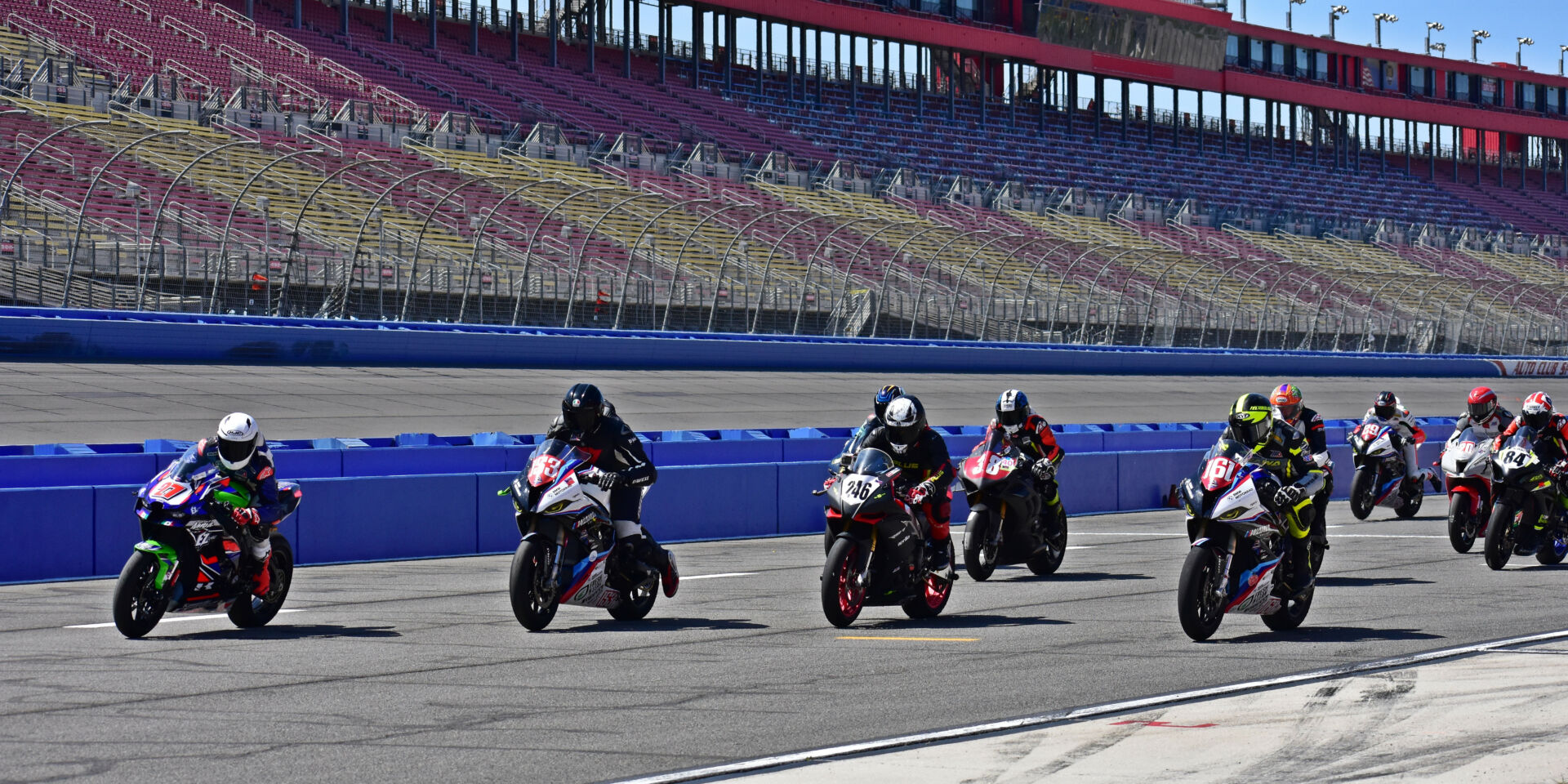 Edgar Zaragoza (27) leads Terry Heard (153), Dexter Stuart (246), Sahar Zvik (161), Fatih Buyuksonmez (38) and the rest coming off the grid at the start of the A Superstock race at Auto Club Speedway. Photo by Michael Gougis.