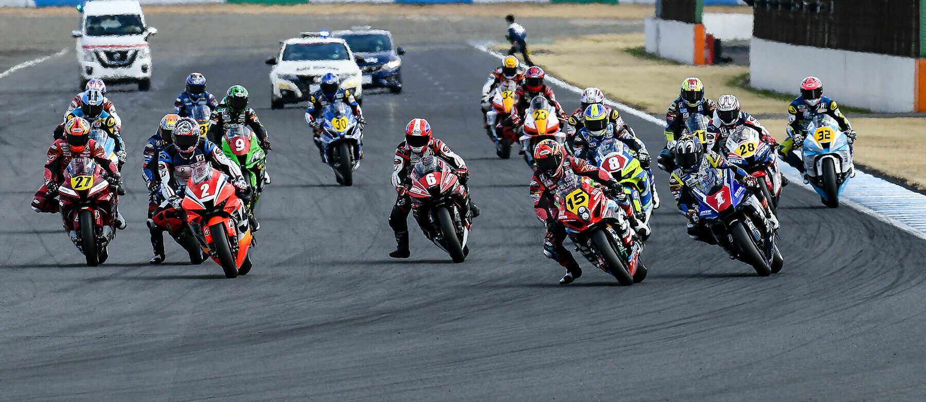 Katsuyuki Nakasuga (1) and Kazuki Watanabe (15) fight for the lead early in Race One at Motegi. Also seen are Kosuke Sakumoto (27), Sodo Hamahara (2), Akira Yanagawa (9), Yuda Kamei (6), Satoru Iwata (8), and the rest of the field. Photo courtesy MFJSuperbike.