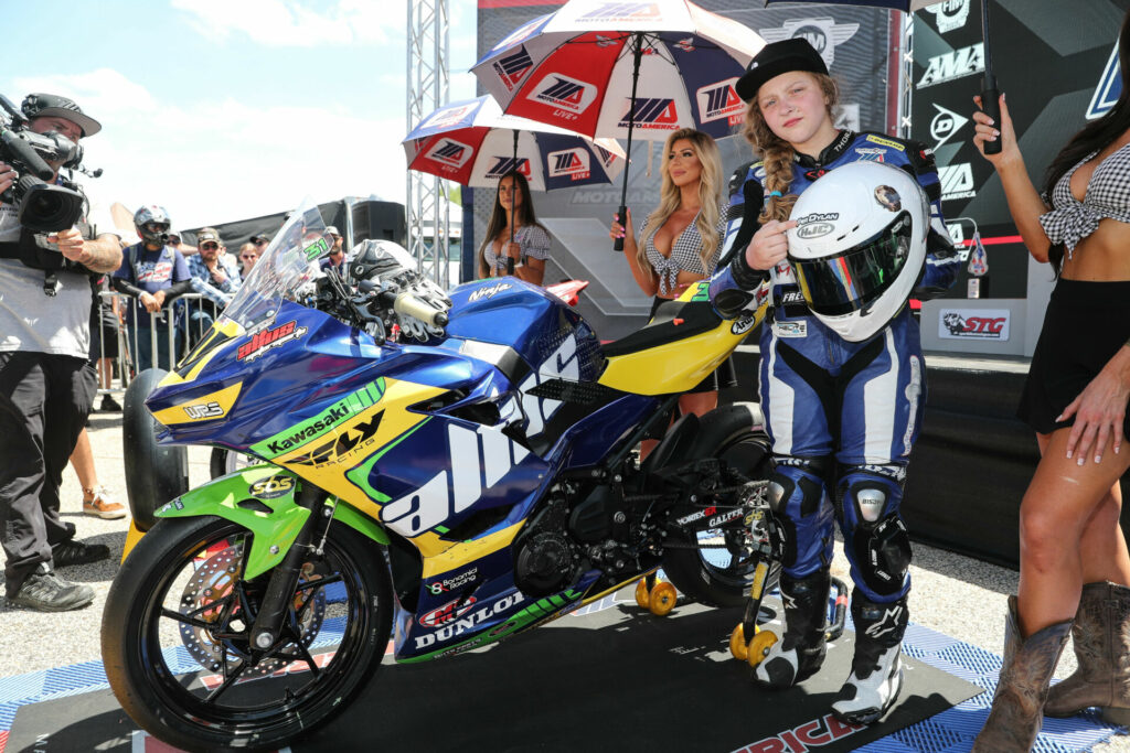 Kayla Yaakov in the podium area at Road Atlanta after Junior Cup Race Two. Yaakov is pointing to the "For Dylan" sticker on her helmet honoring her recently deceased brother Dylan Quaid. Photo by Brian J. Nelson.