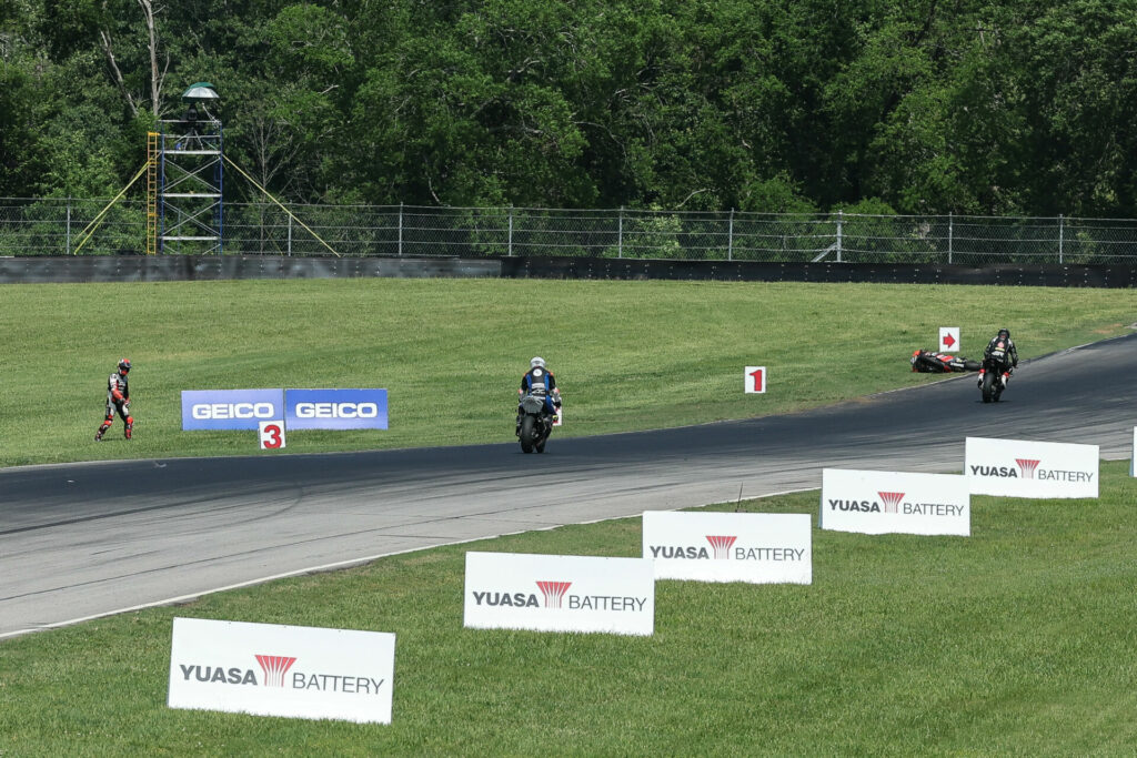 Danilo Petrucci, 67 seconds after he crossed the finish line, standing and looking to cross the racetrack while other riders begin their cool-down laps. Photo by Brian J. Nelson.