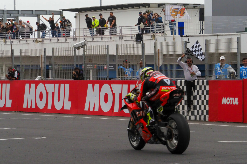 Alvaro Bautista (19) takes the checkered flag at the end of Race One at Estoril. Photo courtesy Dorna.