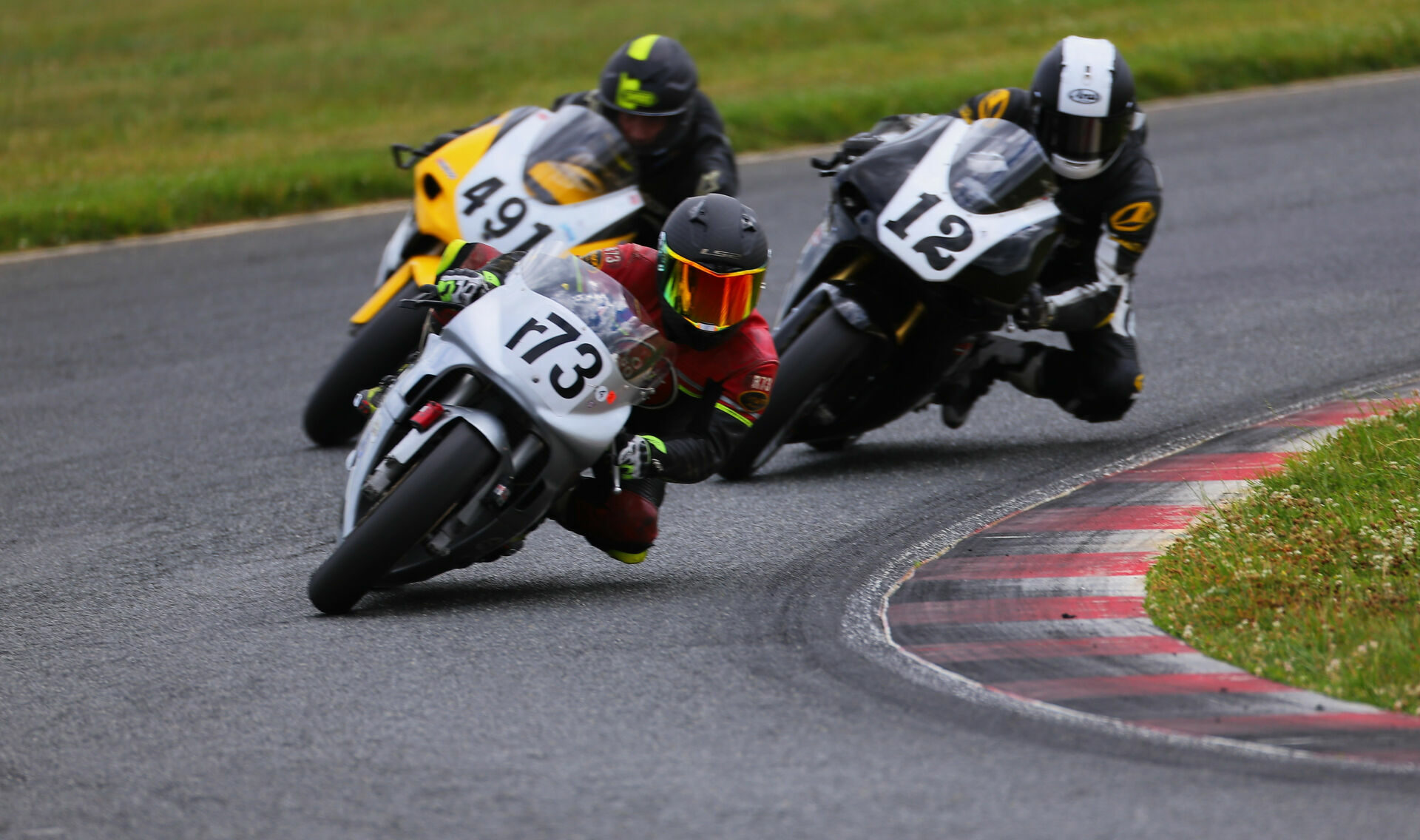 Greg Glevicky (r73), Adrian Jasso (12), and Frank Schoenbeck (491) battle for podium positions in an AHRMA Open Two-Stroke race at New Jersey Motorsports Park. Photo by etechphoto.com, courtesy AHRMA.
