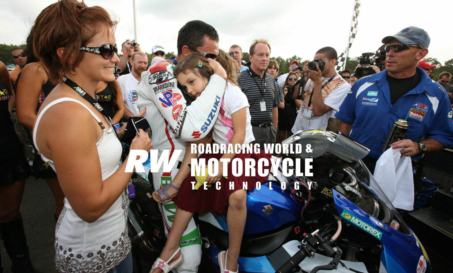 With then-wife Janine (far left) looking on, Mat Mladin embraces his two young daughters after finishing second in AMA Pro America Superbike Race Two at New Jersey Motorsports Park in 2009. It was Mladin's final AMA Superbike race before retiring. Photo by Brian J. Nelson.