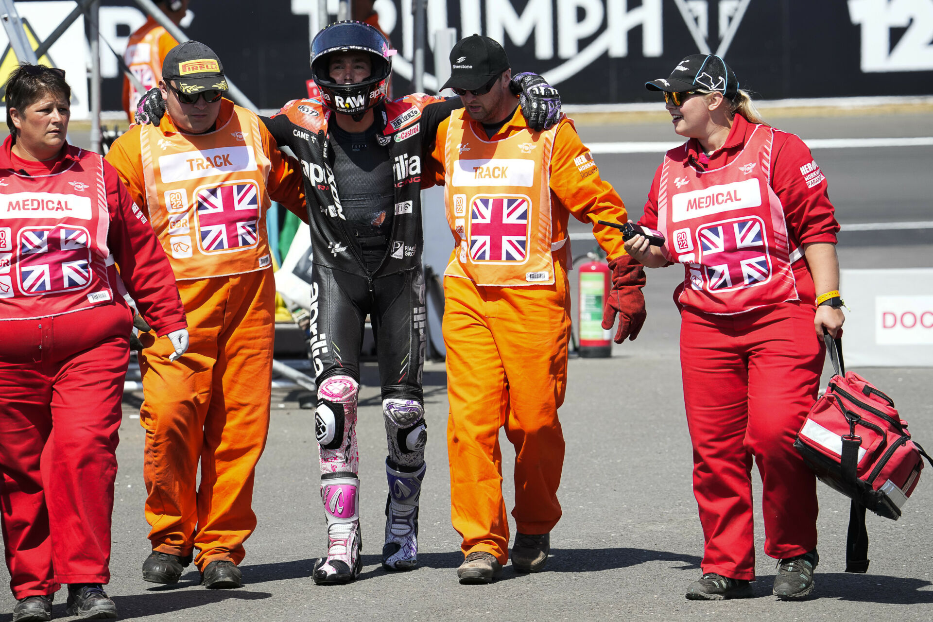 Aleix Espargaro walking with the assistance of corner marshals after crashing Saturday at Silverstone. Photo courtesy Aprilia.