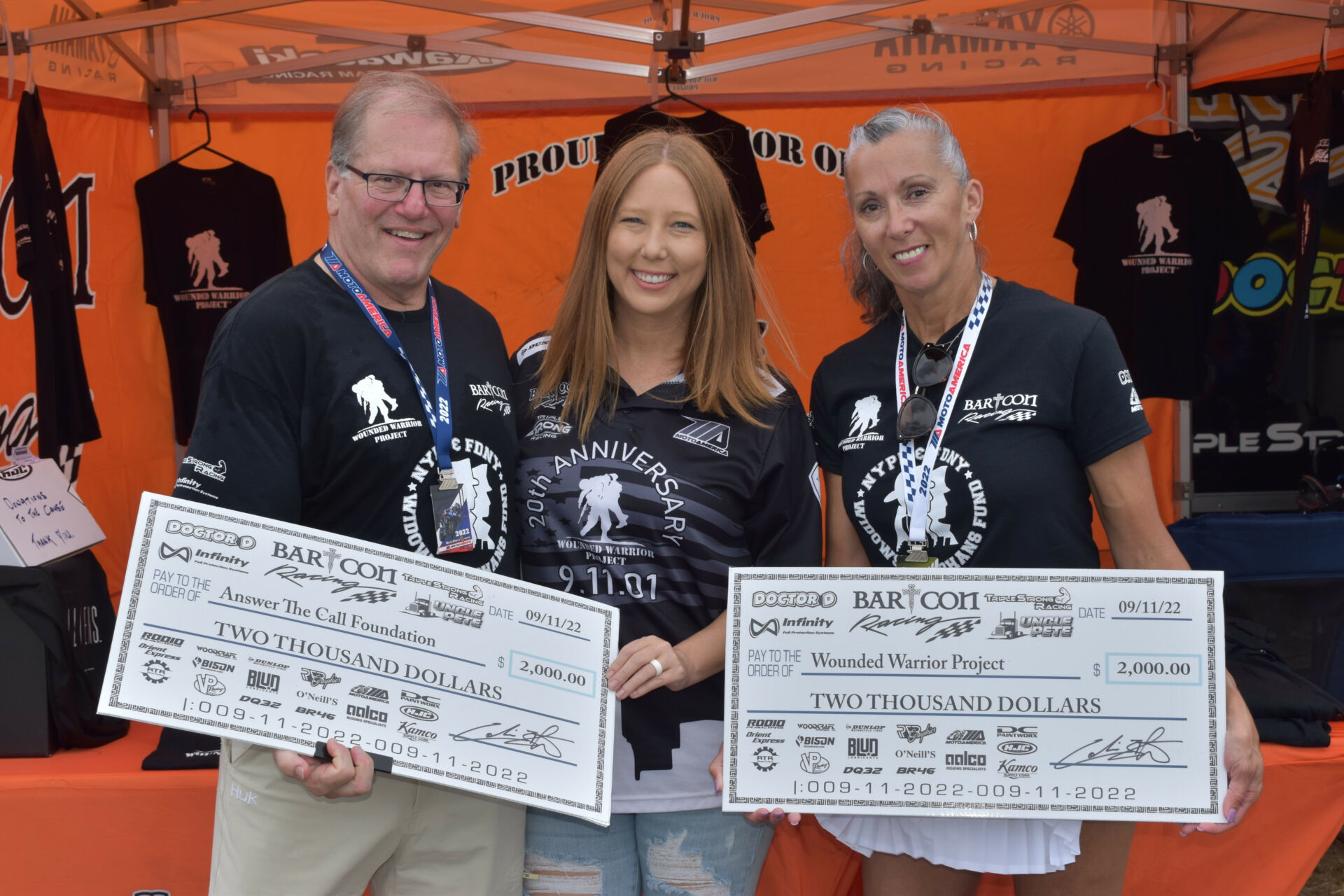 Tosha Lackey (center) accepts checks on behalf of both The Wounded Warrior Project and Answer the Call Foundation from Dr. Mark 