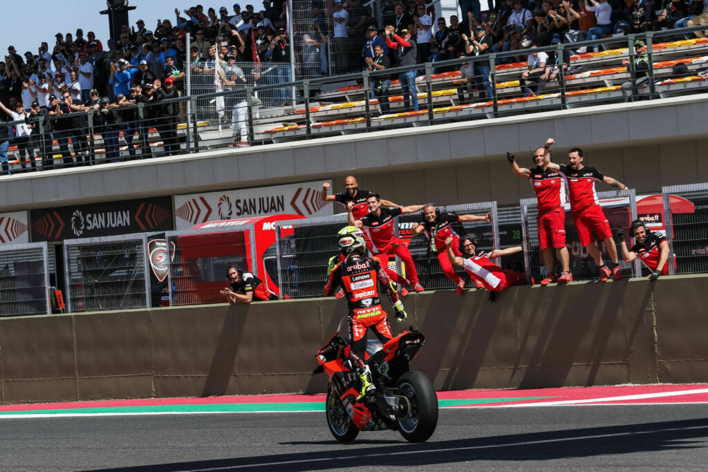 Alvaro Bautista (19) celebrates his Race One victory with his team. Photo courtesy Dorna.