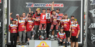 Tyler O'Hara holds up his new #1 plate and poses with teammate Jeremy McWilliams and the S&S Cycle team after winning the 2022 MotoAmerica King Of The Baggers Championship at New Jersey Motorsports Park. Indian Vice President Gary Gray is seen above the #1 plate. Photo by Brian J. Nelson.
