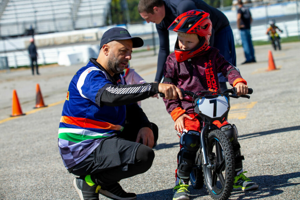 In addition to safety gear and the StaCycs, NEMRR provides volunteers to offer supervision and some instruction to riders. Here, NEMRR racer Sergio DiMolfetta works with a young rider. Photo by Sam Draiss, courtesy NEMRR.