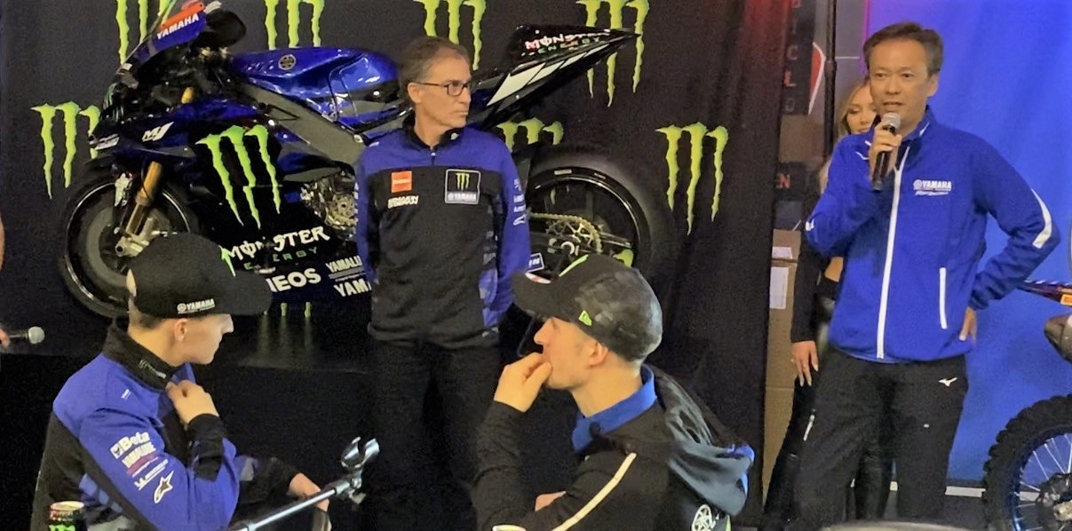 Toyoshi Nishida (far right), Executive Officer and Executive Manager for the Platform Body Development Unit at Yamaha Motor Co., Ltd., speaking during a Yamaha Racing/Monster Energy media event January 20 in San Diego, California. Listening are Yamaha Motor Racing Managing Director Lin Jarvis (second from left), Fabio Quartararo (far left), and Monster Energy Yamaha FIM Motocross World Championship rider Jeremy Seewer (second from right). Still image from video taken by David Swarts.