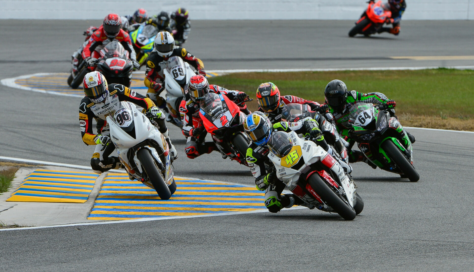 MotoAmerica has banned the use of lithium polymer batteries on racebikes. This photo shows action from the 2022 Daytona 200 with Cameron Petersen (45) leading Brandon Paasch (96), Richie Escalante (behind Petersen), Max Angles (64), Josh Herrin (2), Danny Eslick (69), Geoff May (99), and Josh Hayes (4). Photo by Brian J. Nelson, courtesy MotoAmerica.