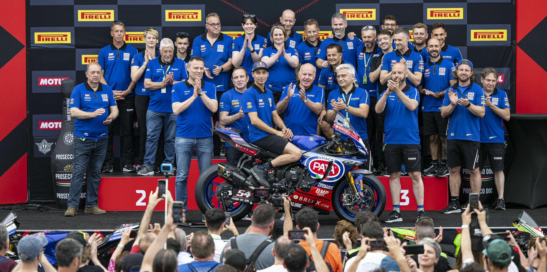 Toprak Razgatlioglu with his 2021 Superbike World Championship-winning Yamaha YZF-R1 and his team on the podium at Misano. Photo courtesy Yamaha.