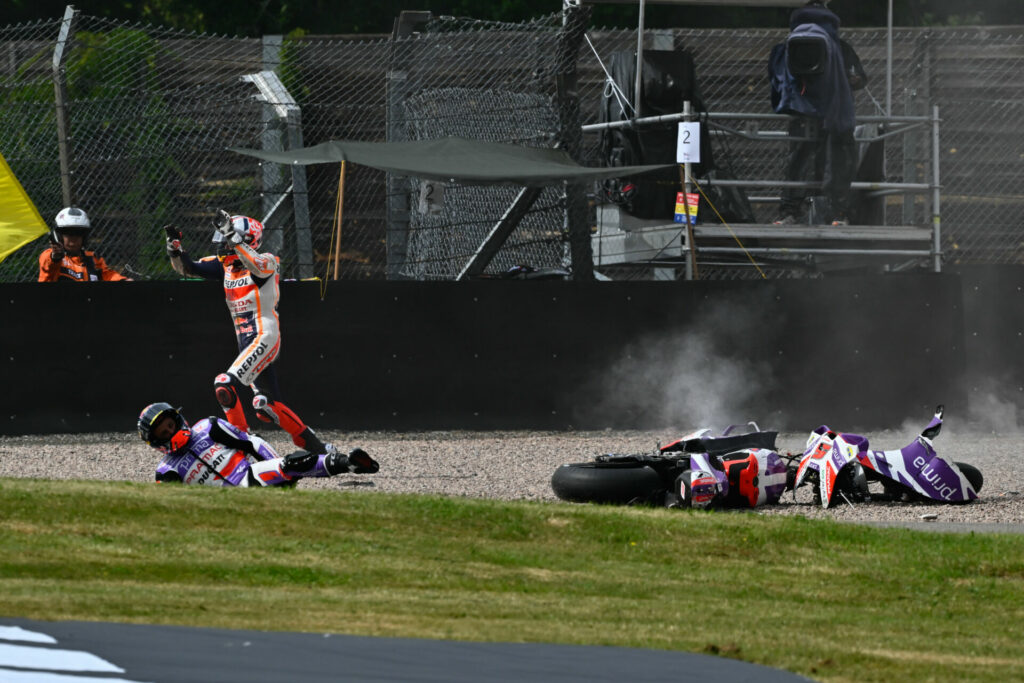 Johann Zarco remains lying on the ground after Marc Marquez (running out of the gravel trap) crashed and collided with him in Turn One. Both escaped injury. Photo courtesy Dorna.