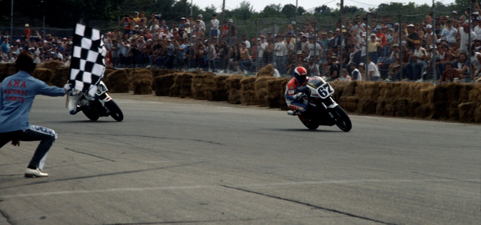 Bubba Shobert (67) takes the checkered flag ahead of Dale Quarterley (32) at the 1986 Loudon AMA Superbike race. Call them crude, but the hay bales were a significant step forward in rider safety at the time. Photo by Larry Lawrence.
