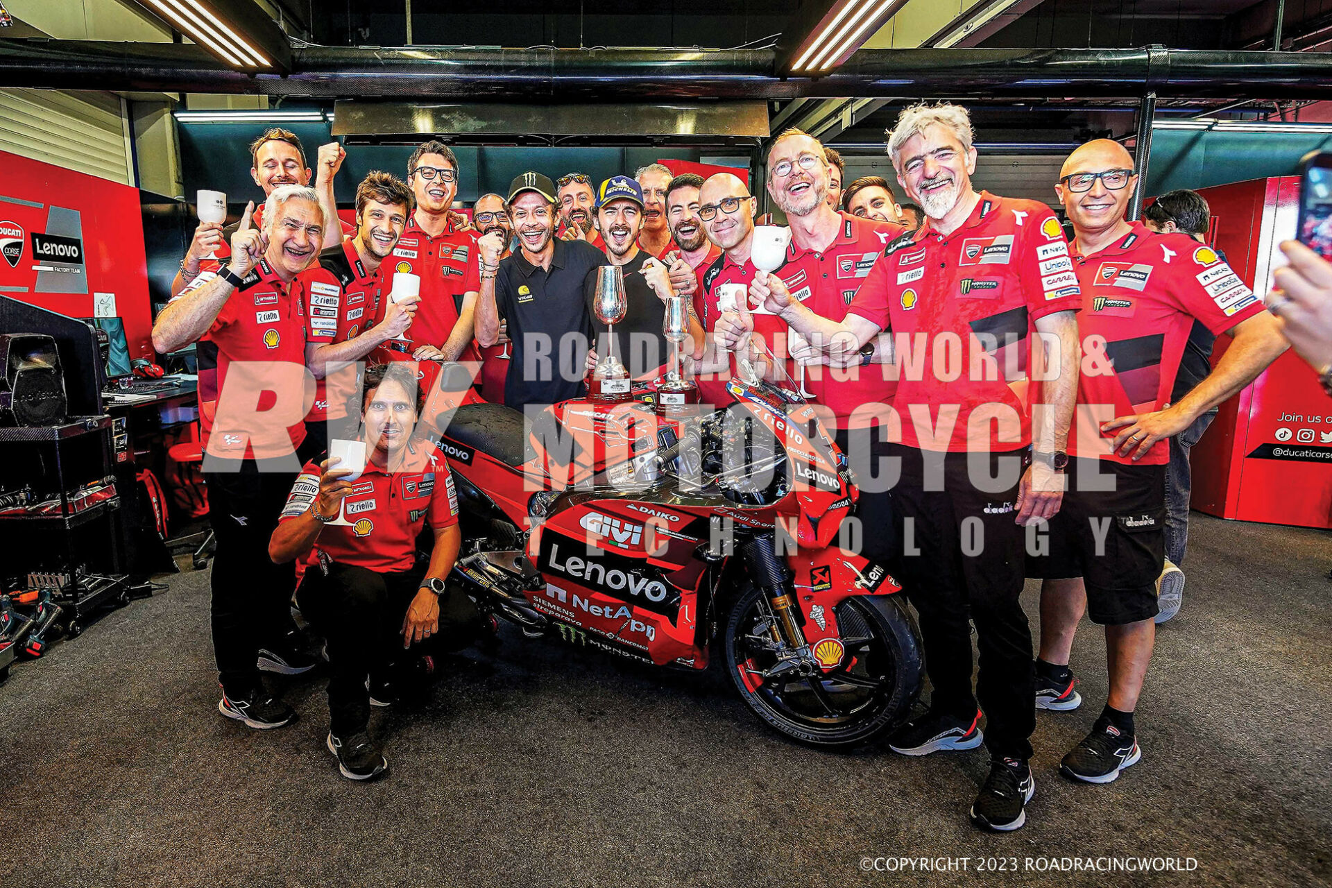 Francesco Bagnaia and mentor Valentino Rossi (in black) celebrate a Jerez win with the Ducati crew. Team Manager Davide Tardozzi is at far left and Ducati Corsa General Manager Gigi Dall'Igna is second from right.