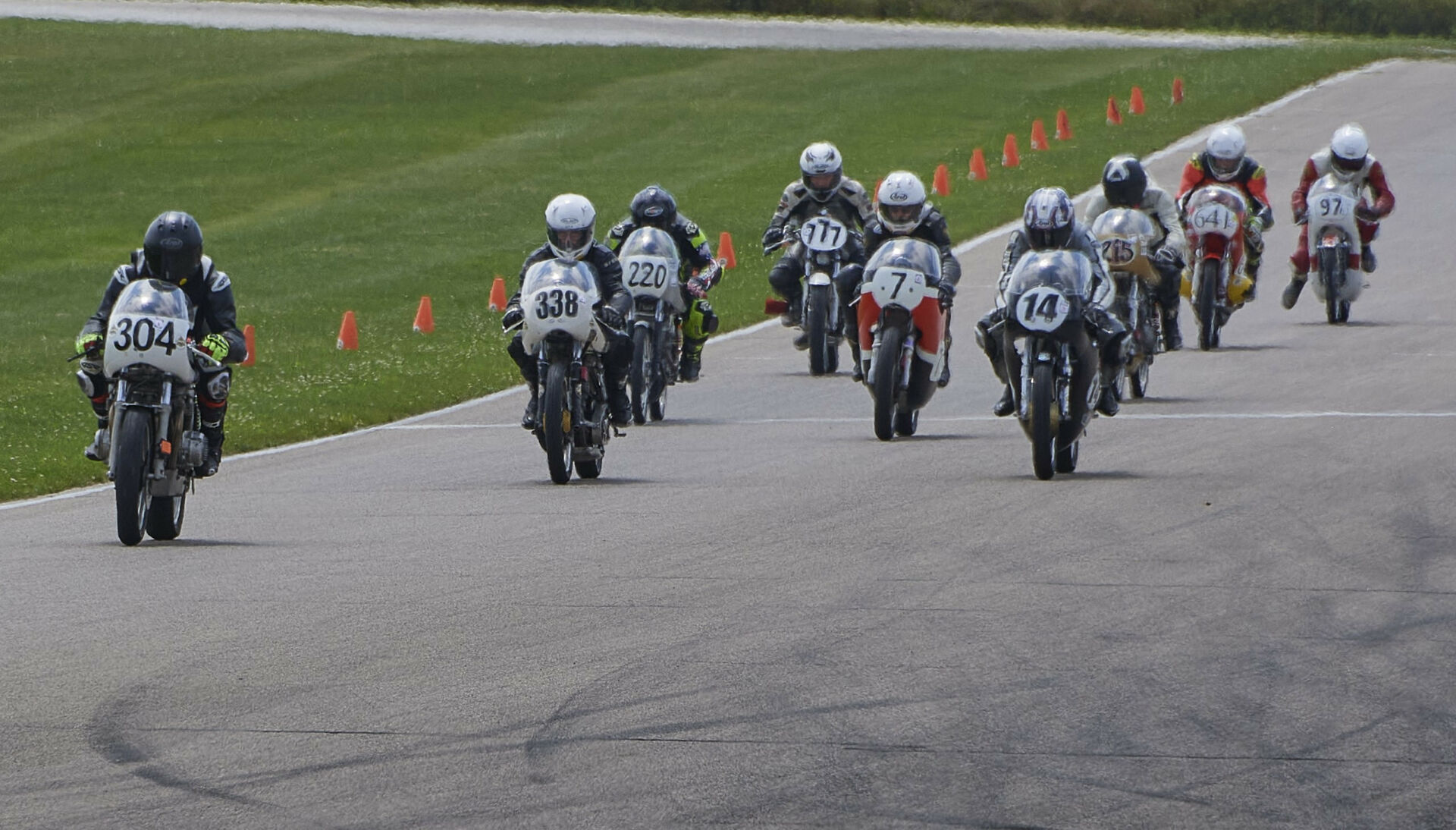 The start of an AHRMA race at Gingerman Raceway with Kevin Dinsmoor (304) leading the combined, three-class field including Andy Findling (338), Tim Terrell (220), Dave Roper (7), Alex McLean (14), Robert Himmelmann (777), Stuart Sanders (215), Craigi Hirko (641), and David Rhodes (97) into Turn One. Photo by Bill Griffin, courtesy AHRMA.