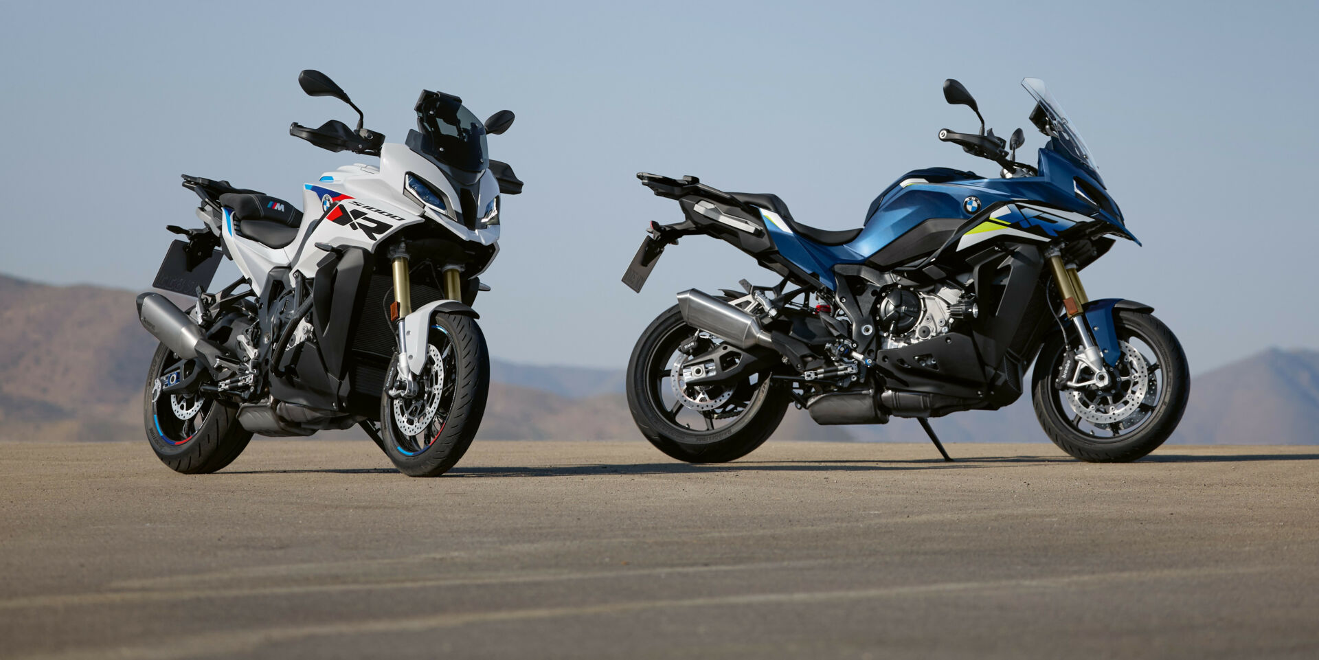 A 2024 BMW S 1000 XR in Gravity Blue Metallic (right) and a 2024 BMW S 1000 XR in Light White/M Motorsport (left) fitted with M Package equipment like the Sport Muffler and M Carbon Wheels. Photo courtesy BMW Motorrad.