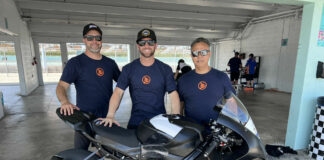 OrangeCat Racing rider Travis Wyman (center) poses with his crew chief Joel Martens (left), mechanic Alex Torres (right), and one of the team's BMW M 1000 RRs. Photo courtesy OrangeCat Racing.