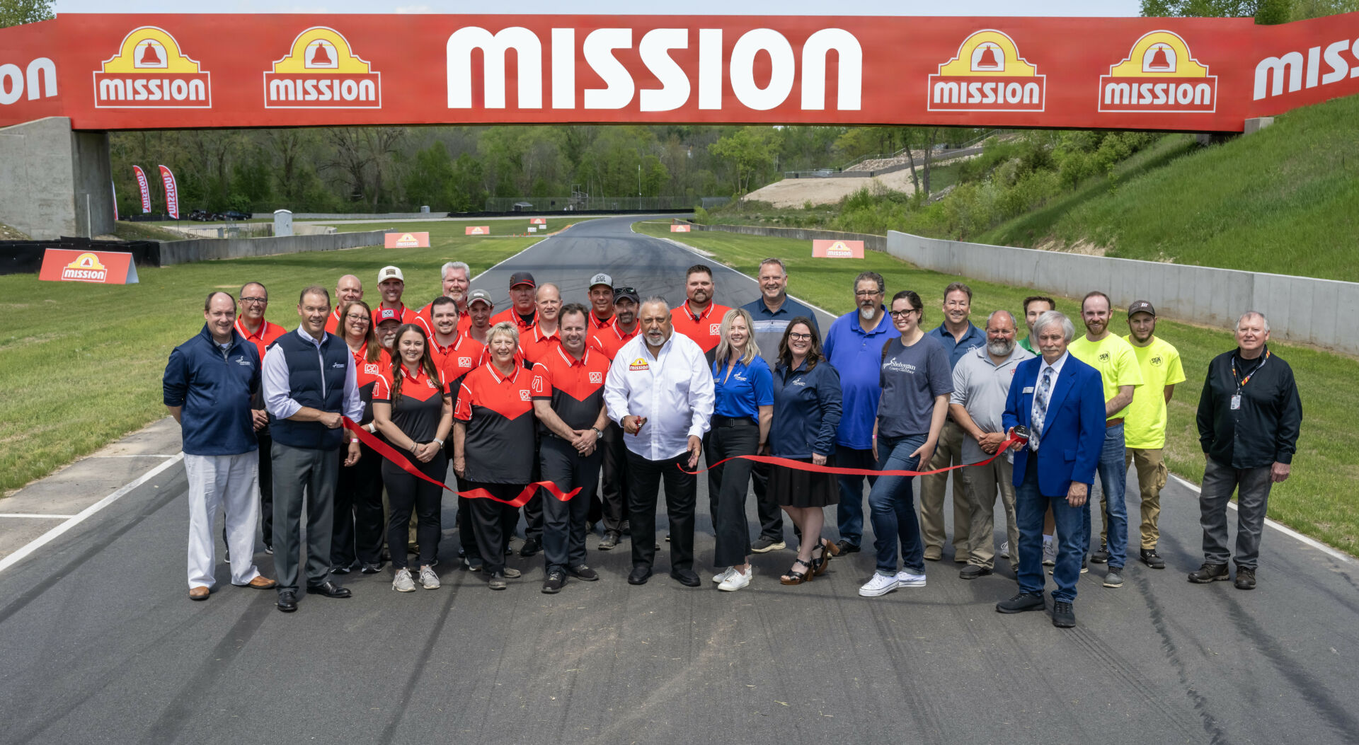 Mission Foods CEO Juan Gonzalez (center in white shirt) cuts a ribbon dedicating the new Mission Bridge and #2Fast2Tasty Beach viewing area at Road America. Photo courtesy Road America.