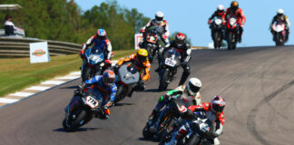 Action from the AHRMA Pro Challenge race in 2023 with Geoff May (99) leading Stefano Mesa (37), Hayden Gillim (77X), Chris Fillmore (11R), Rennie Scaysbrook (33X), Gus Rodio (296), Nate Kern (9T), and the rest. Photo by etechphoto.com, courtesy AHRMA.