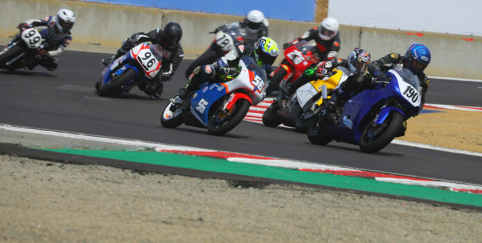 Open 2-stroke Action from the Open Two-Stroke race at the AHRMA Classic MotoFest™ of Monterey in 2023 with Rick Delgado (190) leading Stephen Gillen (56), David Dold (96), Jonathan Schendel (99), Ed Sorbo (78E), Darrell Baker (256), and the rest at WeatherTech Raceway Laguna Seca. Photo by etechphoto.com, courtesy AHRMA.