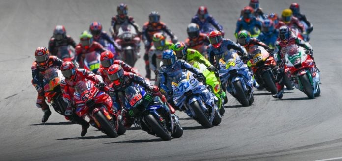 Riders charge into the first corner during a MotoGP race. Photo courtesy Dorna.
